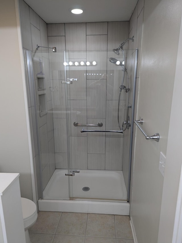 bathroom featuring tile patterned floors, toilet, and a shower with door