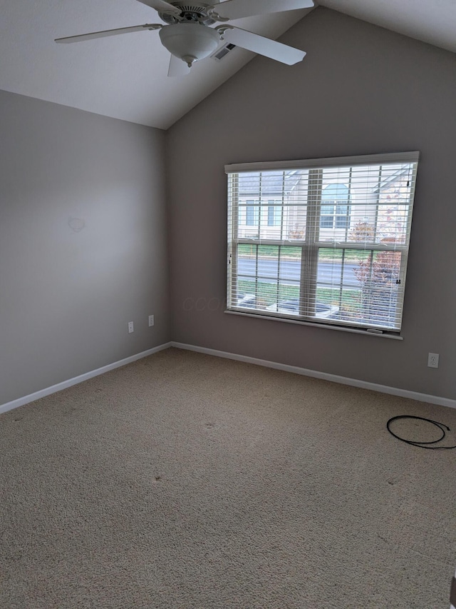 empty room with ceiling fan, plenty of natural light, carpet floors, and vaulted ceiling