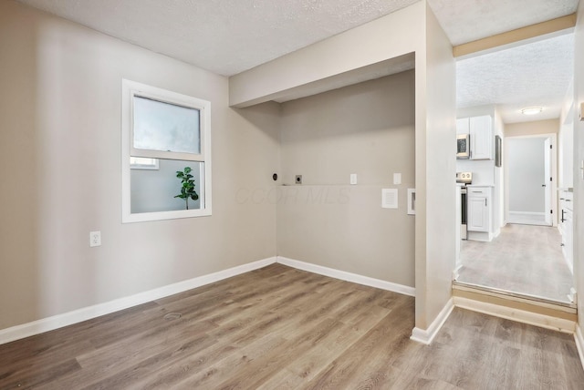 laundry area with a textured ceiling and light wood-type flooring