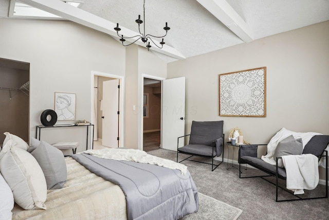 carpeted bedroom featuring a textured ceiling, lofted ceiling with beams, a notable chandelier, a closet, and a walk in closet