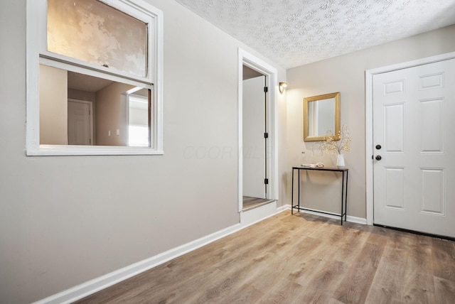 foyer entrance with a textured ceiling and light wood-type flooring