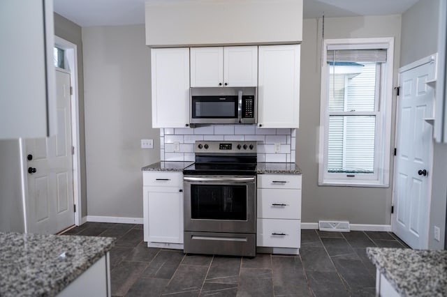 kitchen with dark stone counters, white cabinetry, appliances with stainless steel finishes, and decorative backsplash