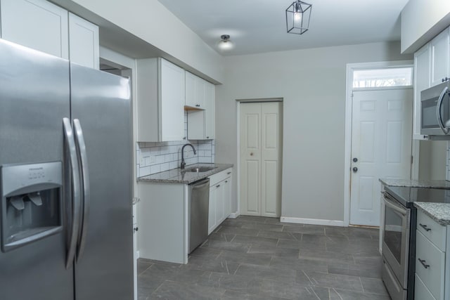 kitchen with appliances with stainless steel finishes, decorative backsplash, white cabinets, sink, and light stone counters