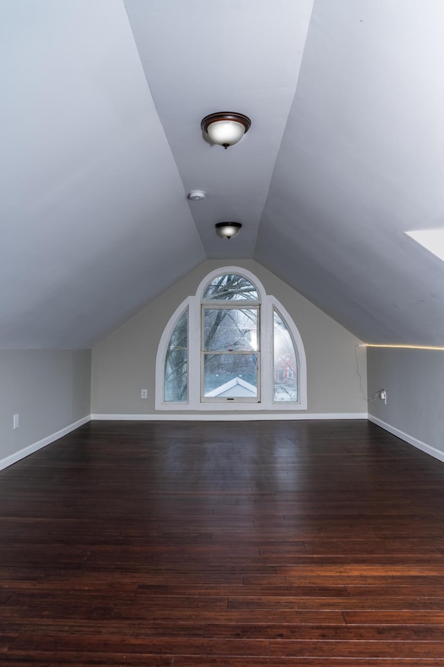 additional living space with vaulted ceiling and dark hardwood / wood-style flooring