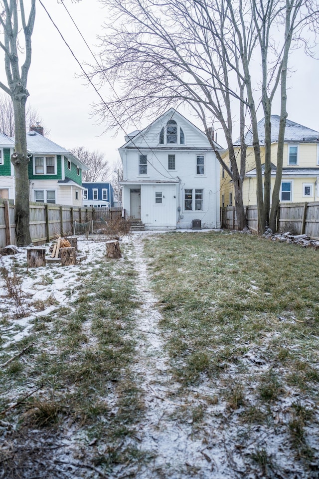 snow covered rear of property with a yard