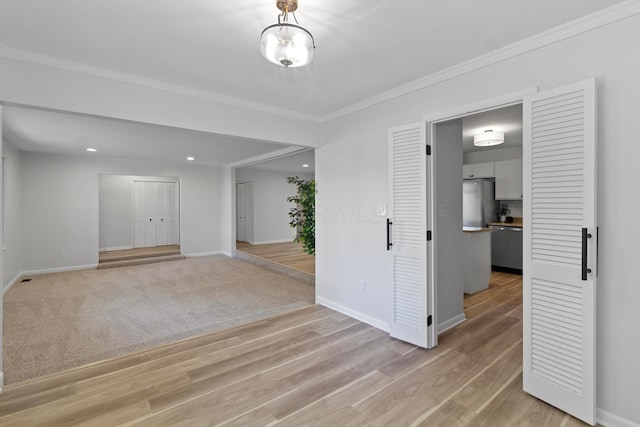 empty room with crown molding and light hardwood / wood-style floors