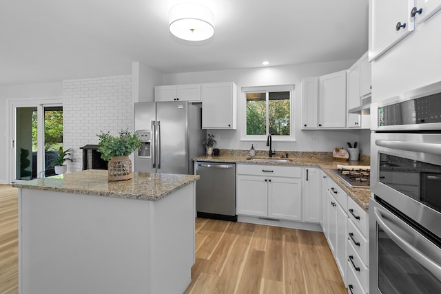 kitchen with white cabinetry, stainless steel appliances, a center island, and sink