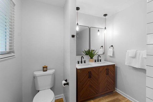 bathroom featuring wood-type flooring, toilet, and vanity