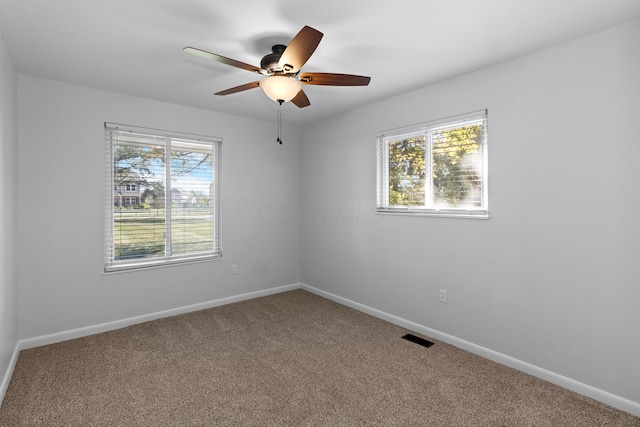 carpeted spare room featuring ceiling fan and plenty of natural light