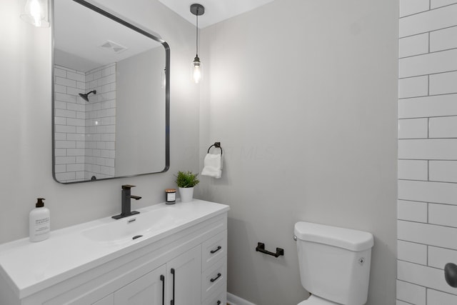 bathroom with vanity, toilet, and a tile shower