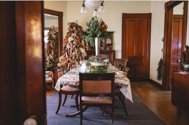 dining area with dark hardwood / wood-style floors and an inviting chandelier