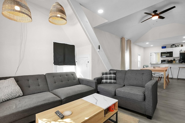 living room featuring ceiling fan, light wood-type flooring, and vaulted ceiling