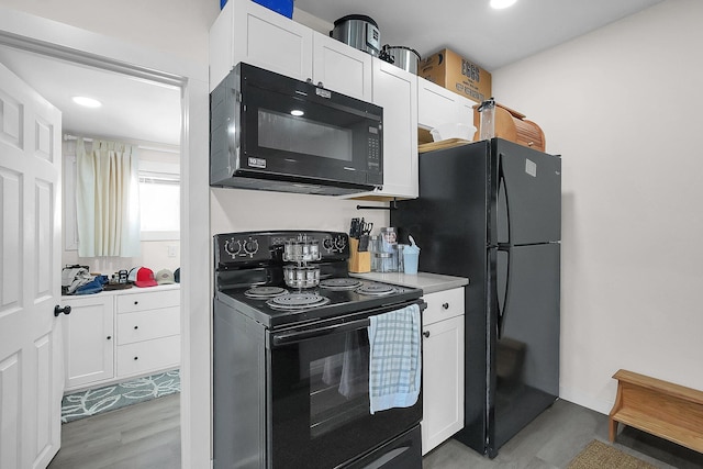 kitchen featuring light hardwood / wood-style flooring, white cabinetry, and black appliances