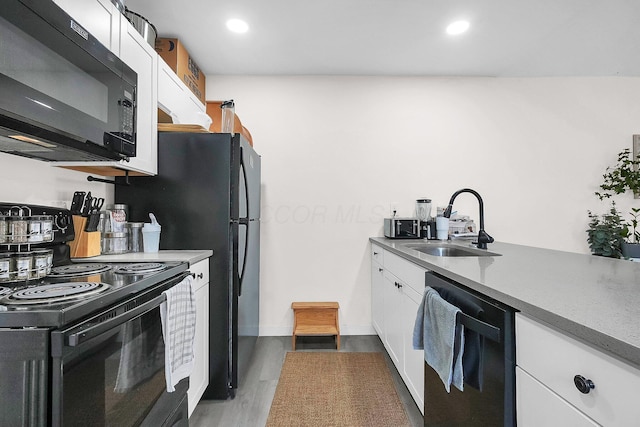 kitchen featuring sink, white cabinets, black appliances, and hardwood / wood-style flooring