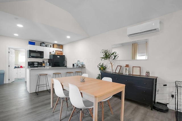 dining room with hardwood / wood-style floors, plenty of natural light, a wall mounted AC, and lofted ceiling