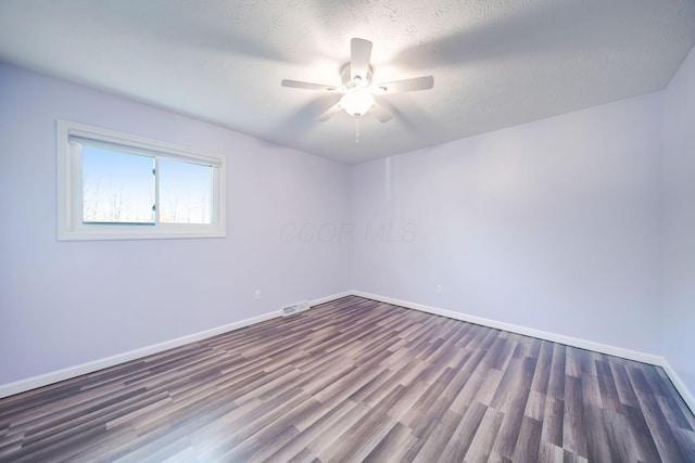 empty room with ceiling fan, dark hardwood / wood-style flooring, and a textured ceiling