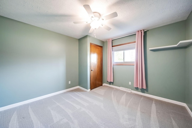 unfurnished bedroom featuring ceiling fan, light colored carpet, and a textured ceiling