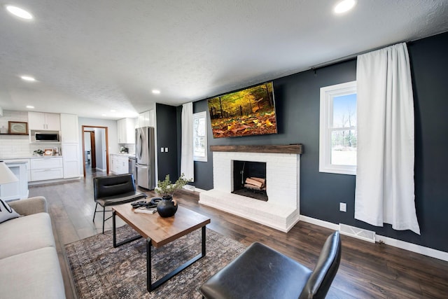 living room with a brick fireplace, dark hardwood / wood-style floors, and a textured ceiling