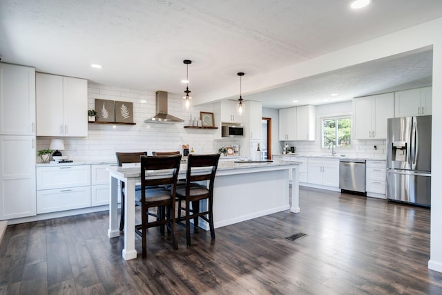 kitchen featuring white cabinetry, appliances with stainless steel finishes, and wall chimney exhaust hood