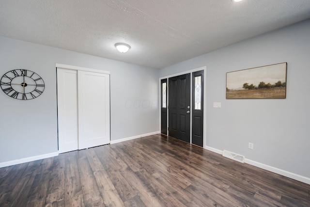 unfurnished bedroom featuring dark hardwood / wood-style floors, a textured ceiling, and a closet