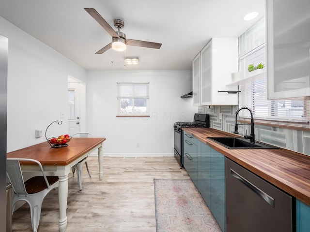 kitchen featuring gas stove, ceiling fan, dishwasher, sink, and wooden counters