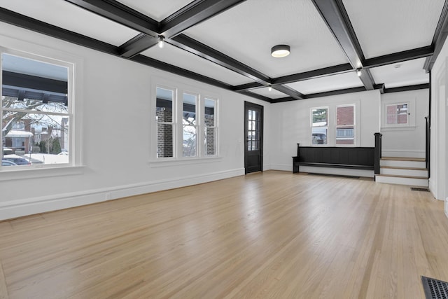 unfurnished living room with beamed ceiling, a healthy amount of sunlight, and coffered ceiling