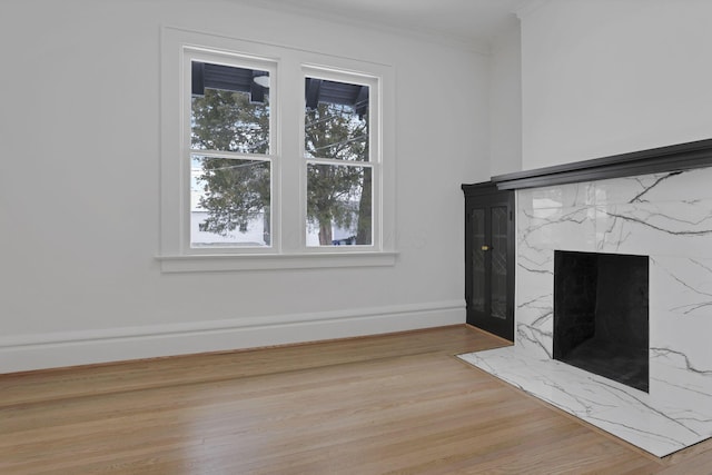 unfurnished living room featuring a premium fireplace, light hardwood / wood-style flooring, and ornamental molding