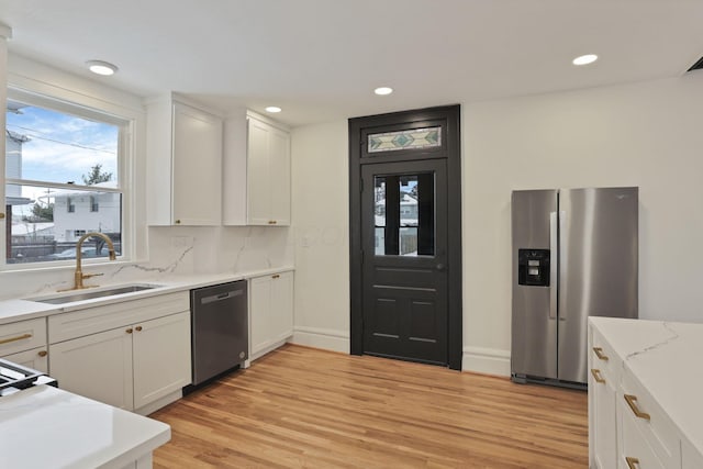 kitchen with sink, stainless steel appliances, backsplash, white cabinets, and light wood-type flooring