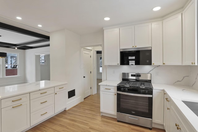 kitchen with white cabinets, appliances with stainless steel finishes, light hardwood / wood-style flooring, and beam ceiling