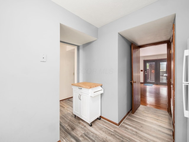 hallway with french doors and light hardwood / wood-style flooring