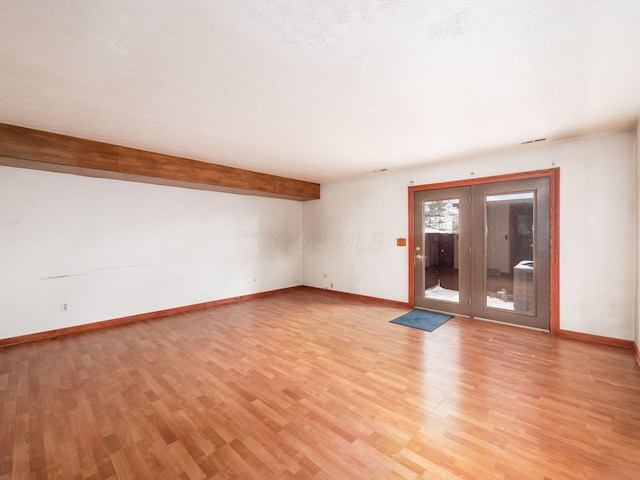 empty room featuring beamed ceiling and light hardwood / wood-style floors