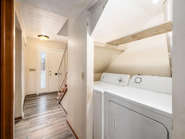 laundry area with washing machine and dryer, a textured ceiling, and light hardwood / wood-style flooring