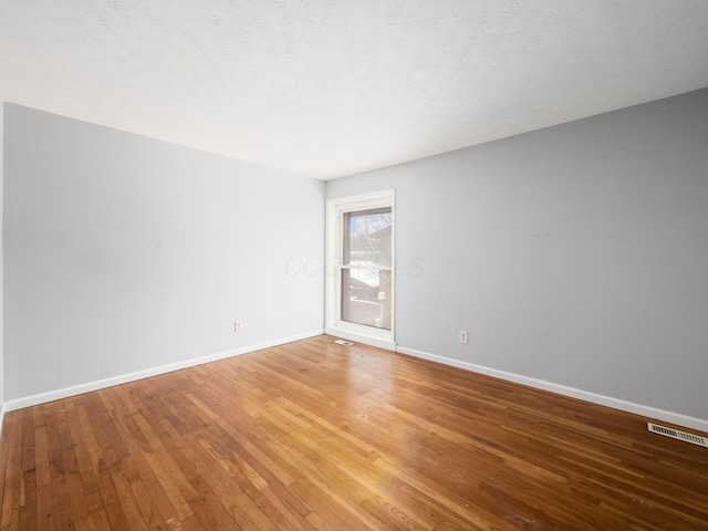 spare room with a textured ceiling and hardwood / wood-style flooring