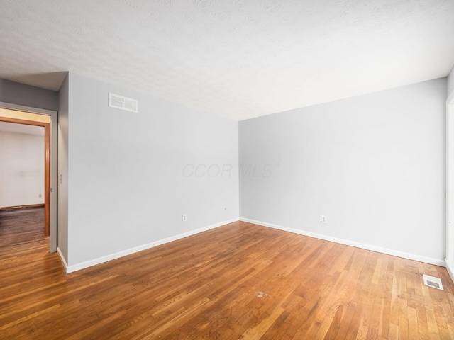 spare room featuring hardwood / wood-style flooring and a textured ceiling