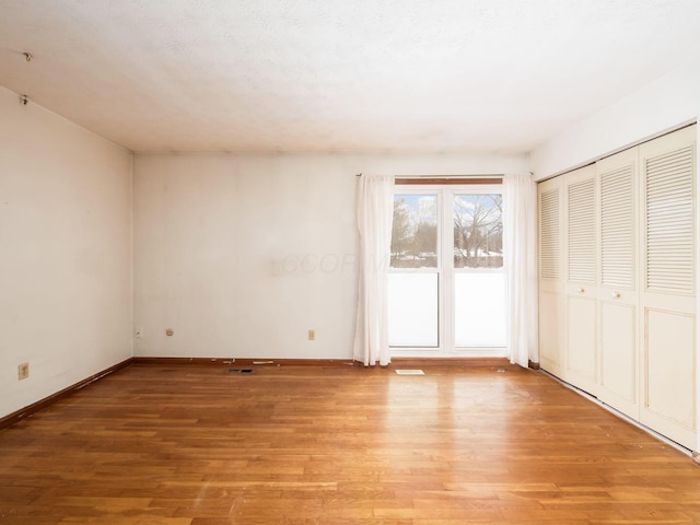 unfurnished room with a textured ceiling and light wood-type flooring