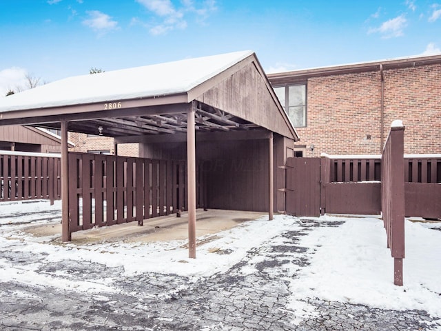 snow covered back of property featuring a carport