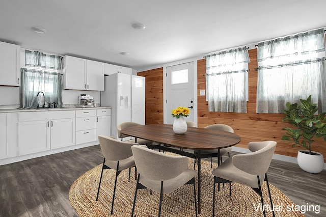 dining space with dark hardwood / wood-style floors, wood walls, and sink