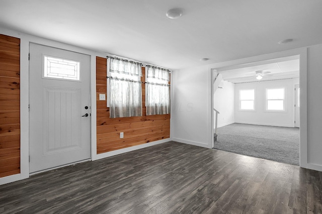 foyer featuring ceiling fan, dark wood-type flooring, and wooden walls