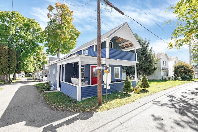 view of front facade featuring a balcony, a front lawn, and covered porch