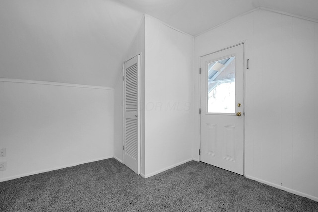 interior space with dark colored carpet and vaulted ceiling