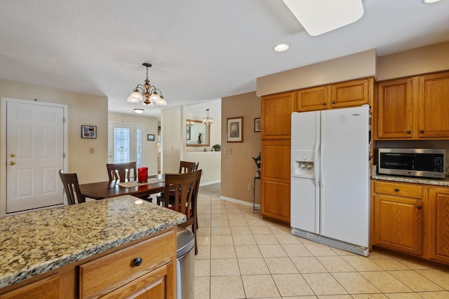 kitchen featuring light stone countertops, white refrigerator with ice dispenser, light tile patterned floors, a chandelier, and hanging light fixtures