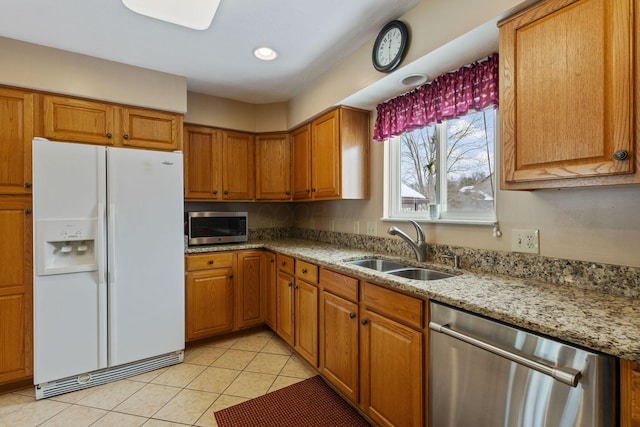 kitchen with light tile patterned floors, light stone countertops, sink, and appliances with stainless steel finishes