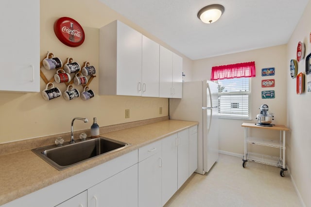 kitchen with white cabinets, white fridge, and sink