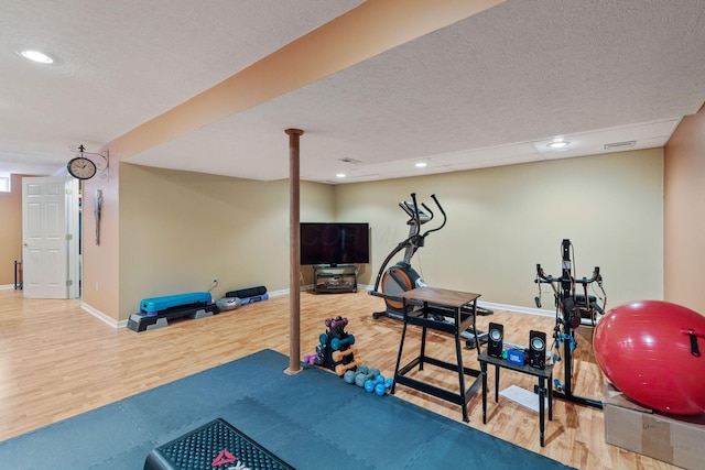 exercise area with hardwood / wood-style floors and a textured ceiling