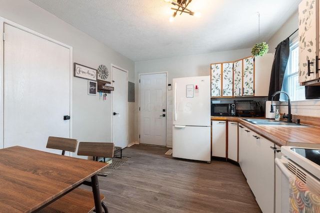 kitchen with stove, dark wood-type flooring, sink, white refrigerator, and white cabinetry