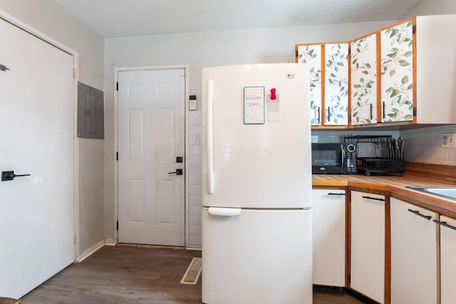 kitchen with dark hardwood / wood-style flooring, backsplash, white refrigerator, electric panel, and white cabinetry