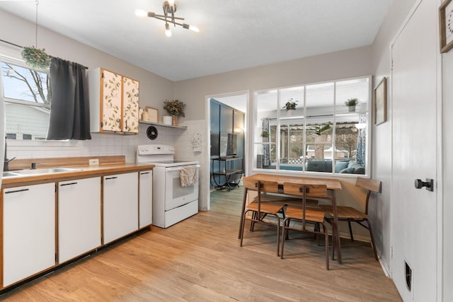 kitchen featuring backsplash, sink, electric stove, white cabinets, and light hardwood / wood-style floors