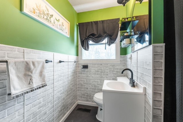 bathroom with tile patterned flooring, vanity, toilet, and tile walls