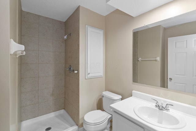 bathroom featuring a tile shower, vanity, and toilet