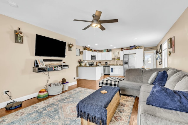 living room with hardwood / wood-style floors, ceiling fan, and sink